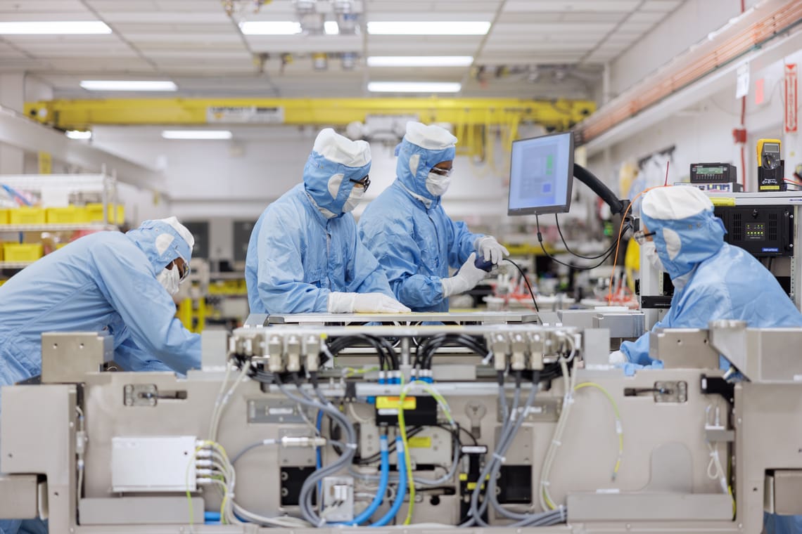 Four cleanroom engineers assembling a DUV lithography reticle stage at ASML’s Wilton facility.
